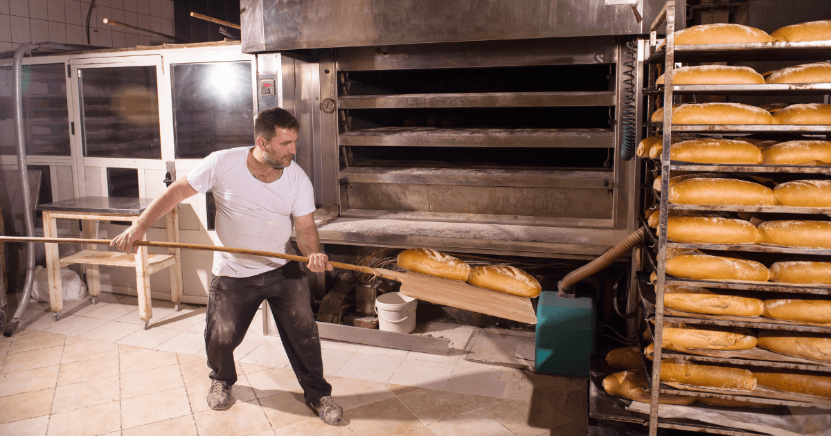 Bakery worker taking out freshly baked breads